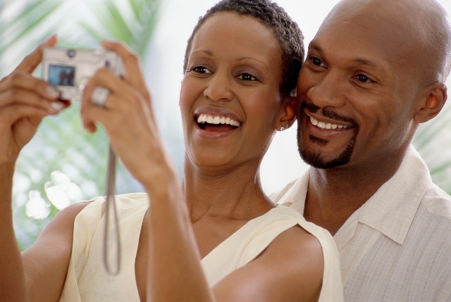 Delighted middle aged black Toronto couple looking at a picture of a new arrival in the family on their cell phone.