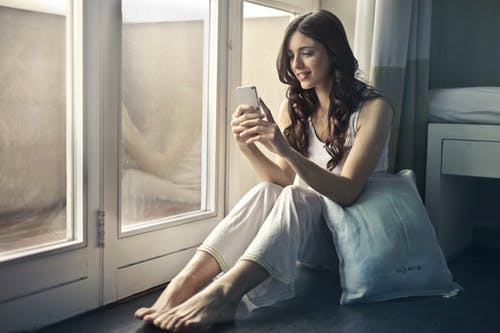 Woman in a long distance relationship talking to her fiance by phone in her pajamas