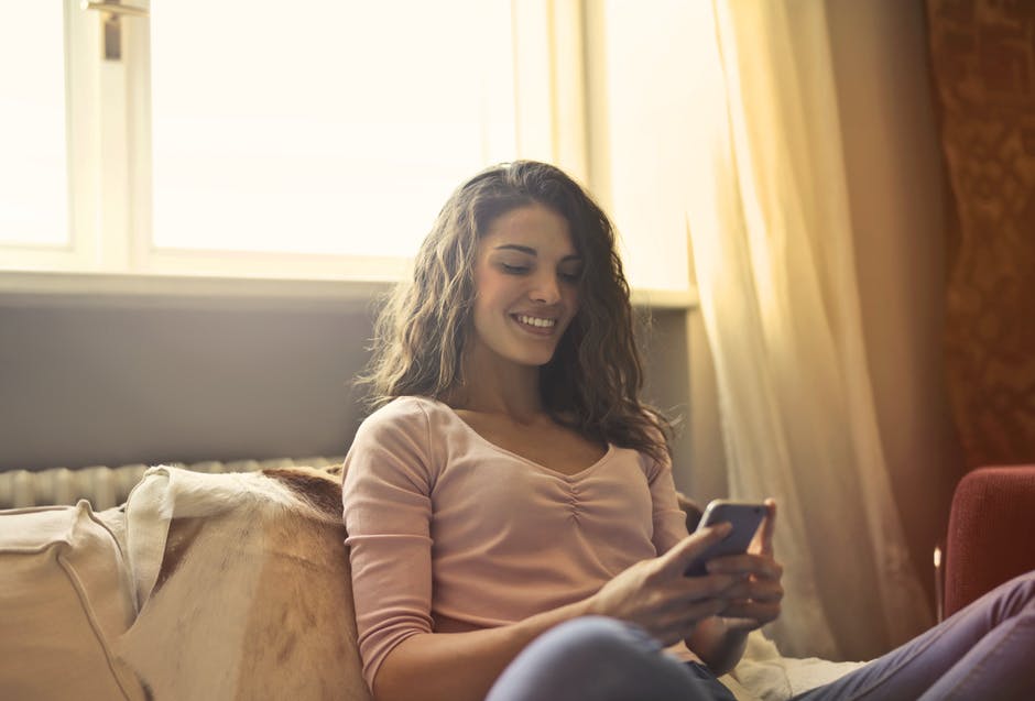 Psychotherapy at home--woman sitting in her living room talking to her online therapist using her smart phone